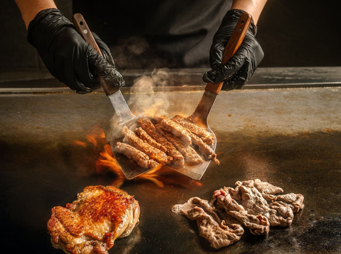 Chef searing meat on the teppan iron